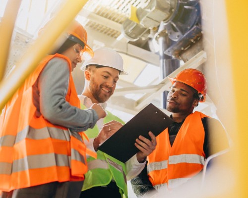 Three people discussing a plan at a factory